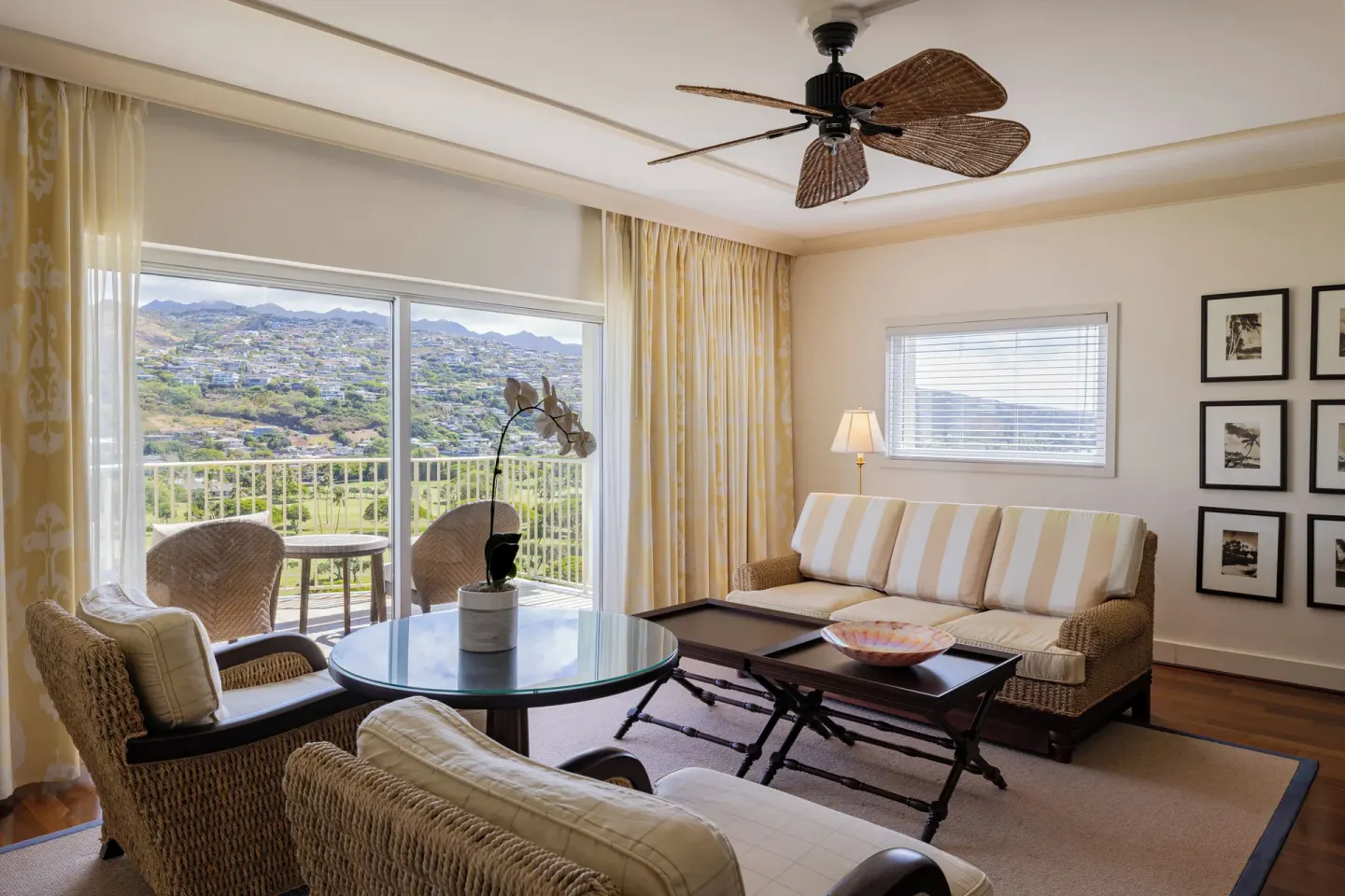 Living room with wicker seating and hillside balcony view at The Kahala Hotel & Resort.