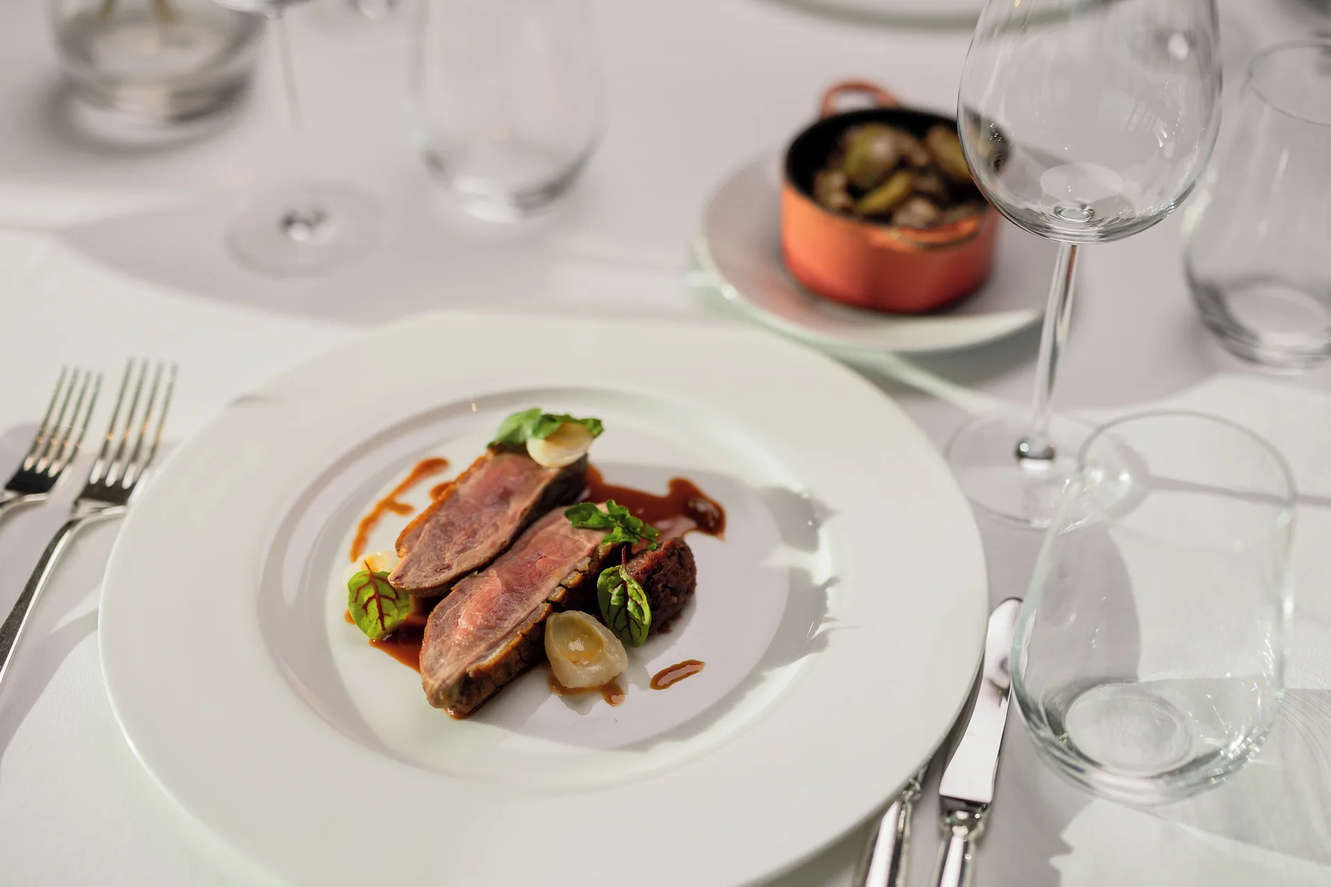 Sliced meat entree with sauce on a white table at The Kahala Hotel & Resort.