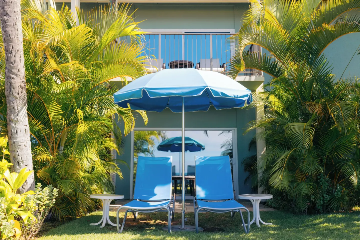 Beach Front Lanai patio with lounge chairs and umbrella at The Kahala Hotel & Resort.