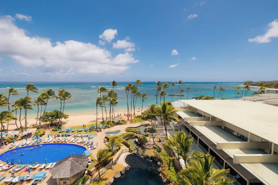 Wide Ocean Front view of pool, beach, palms, and ocean at The Kahala Hotel & Resort.