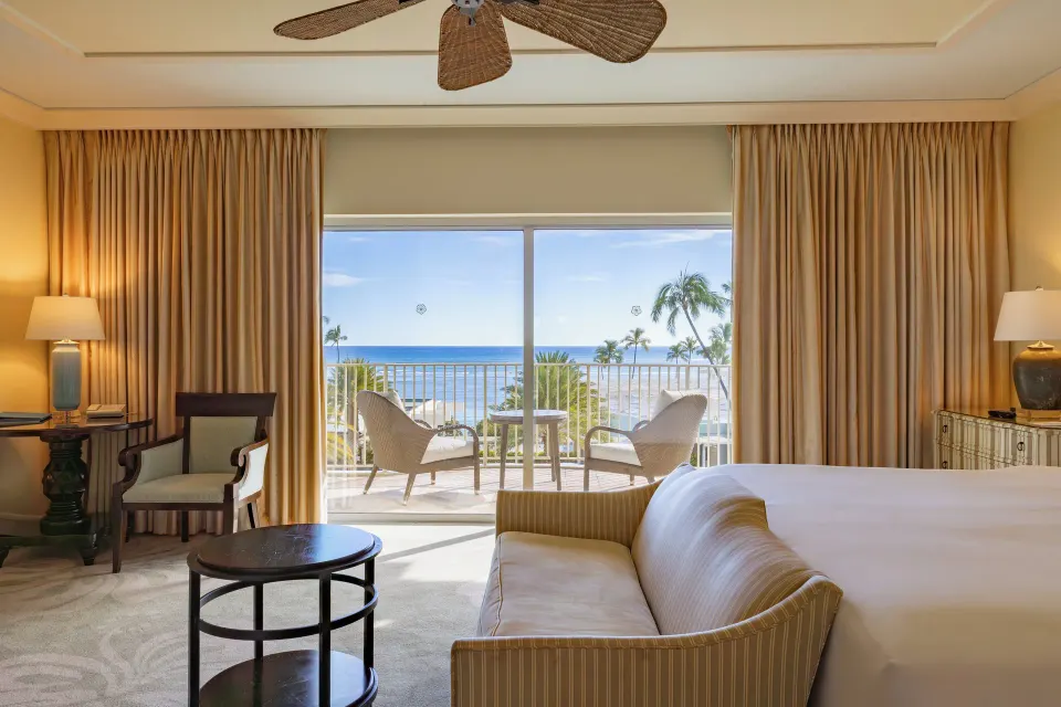 Ocean View Lanai room with bed, sofa, and sunny ocean-facing balcony at The Kahala Hotel & Resort.