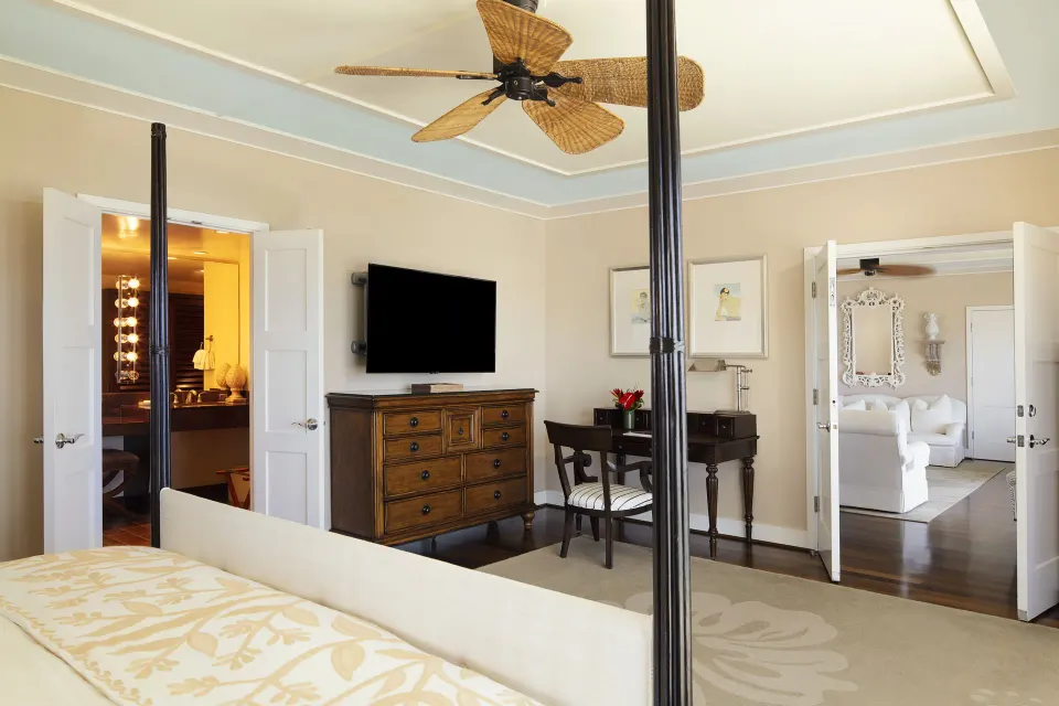 Tower Suite I bedroom with four-poster bed, TV, desk, and open doors at The Kahala Hotel & Resort.