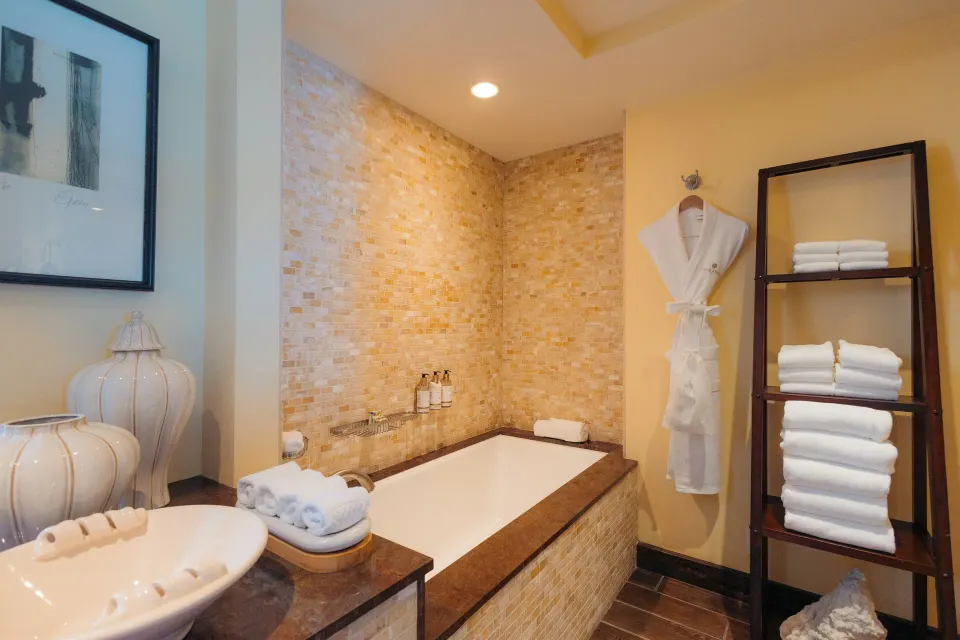 Tower Suite I bathroom tub with towels, robe, and tile surround at The Kahala Hotel & Resort.