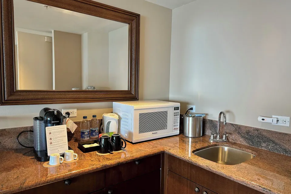 Tower Suite I wet bar with coffee maker, microwave, sink, and mirror at The Kahala Hotel & Resort.