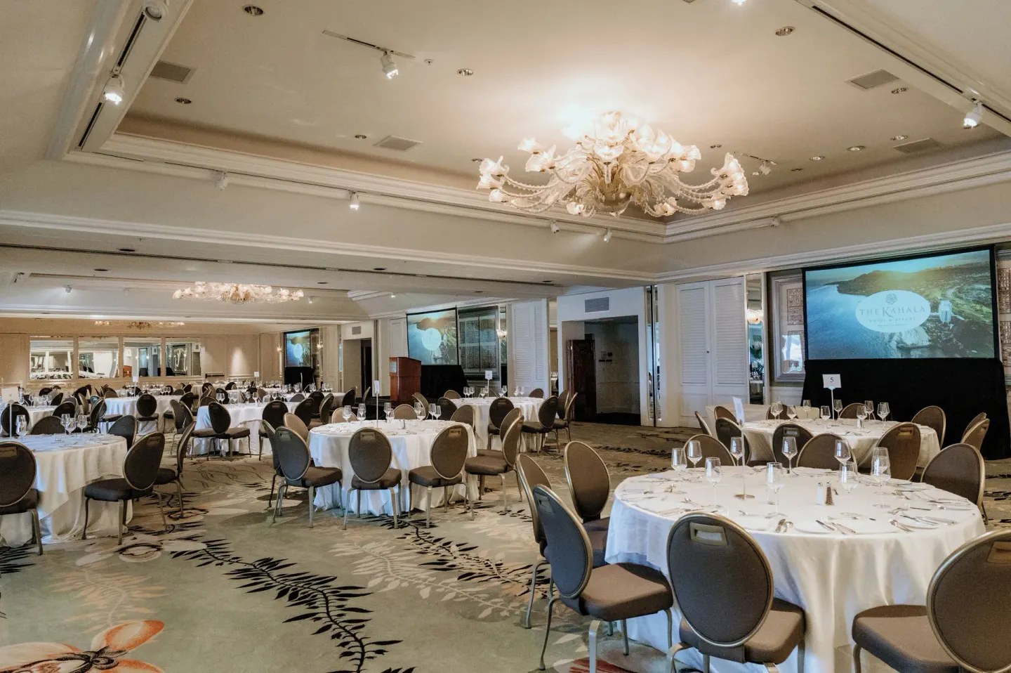 Banquet room with round tables and projection screens at The Kahala Hotel & Resort.