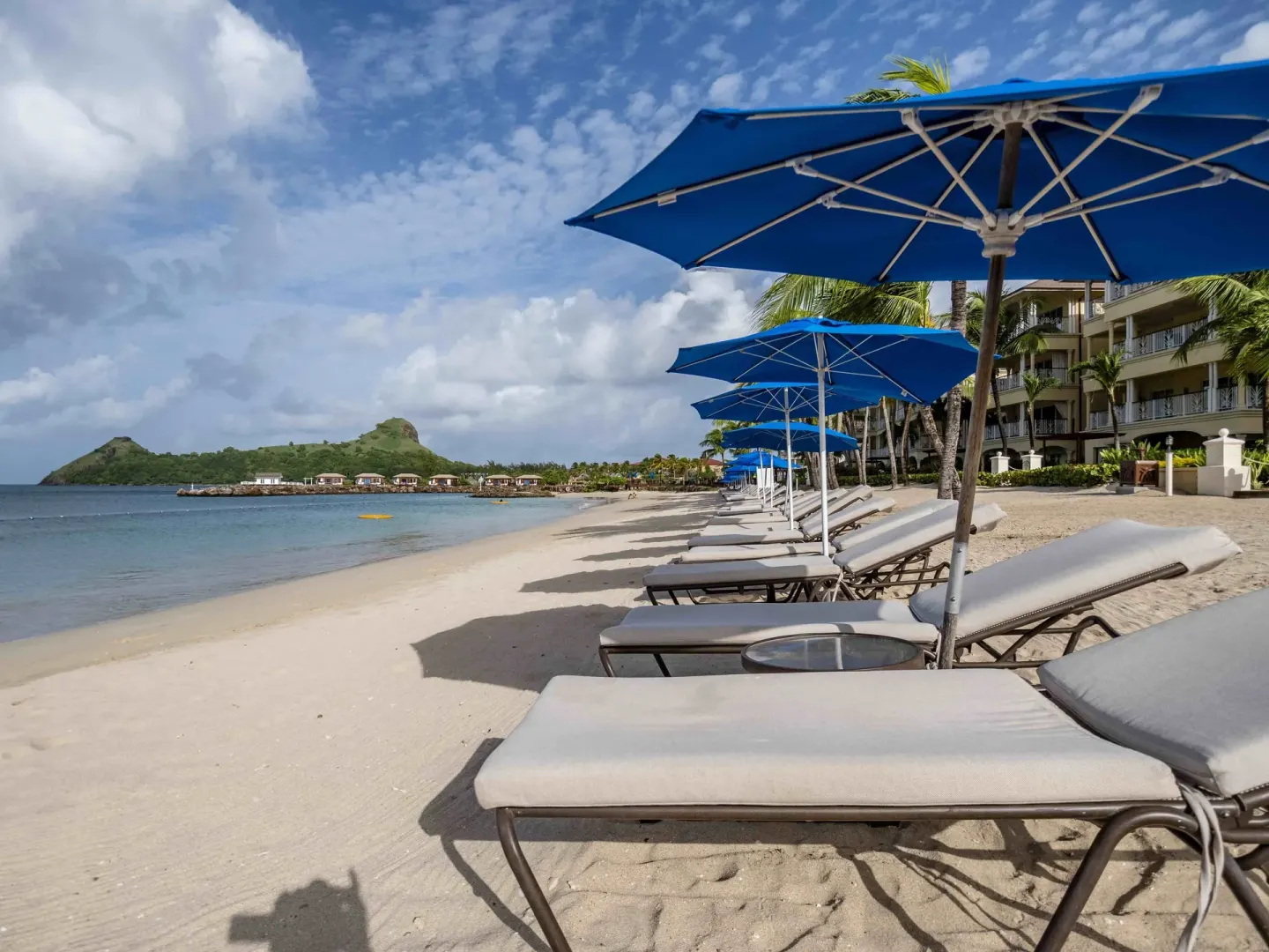 Blue umbrellas shade beach loungers on the sand at The Landings Resort & Spa.