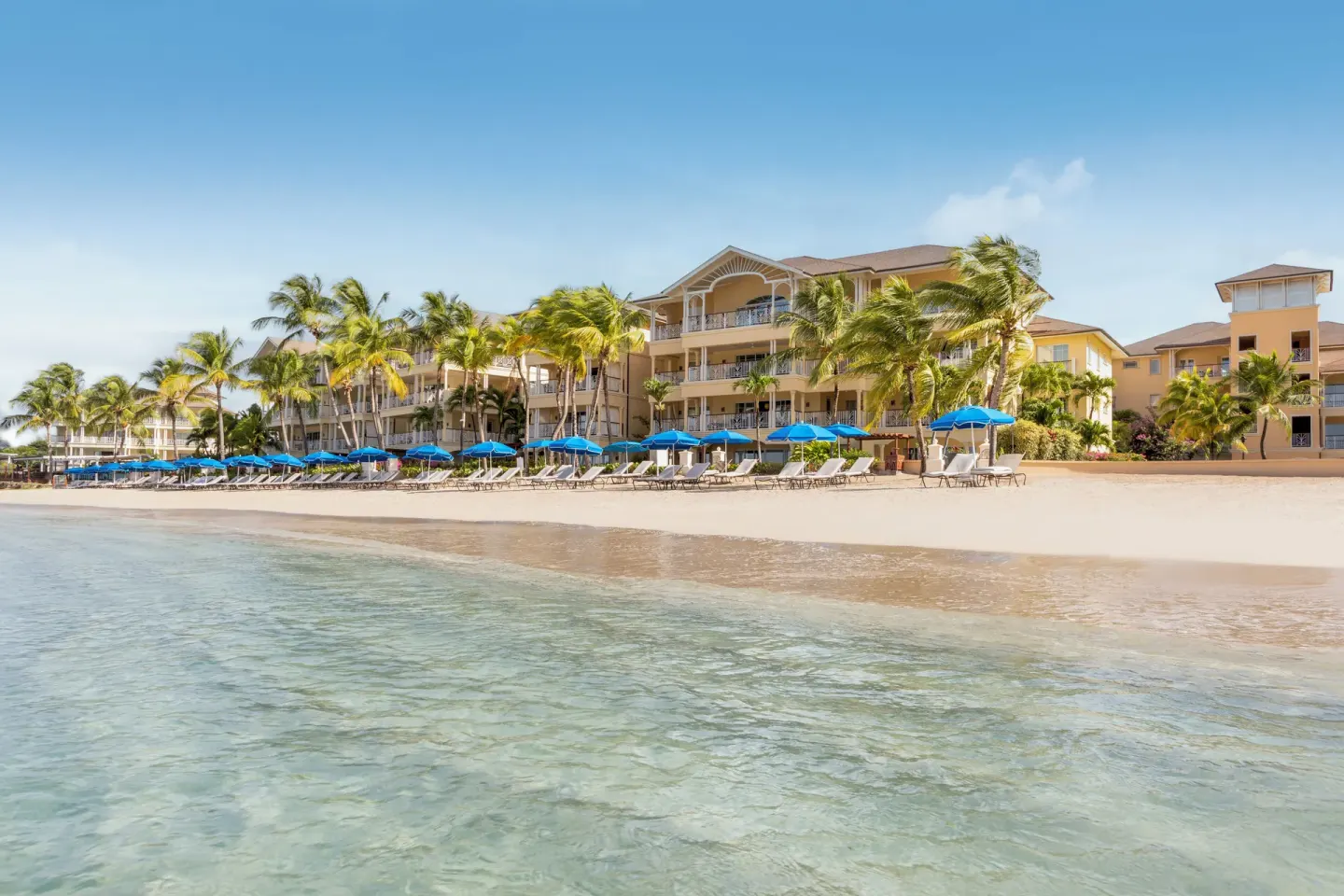 Beachfront resort buildings and blue umbrellas line the shore at The Landings Resort & Spa.