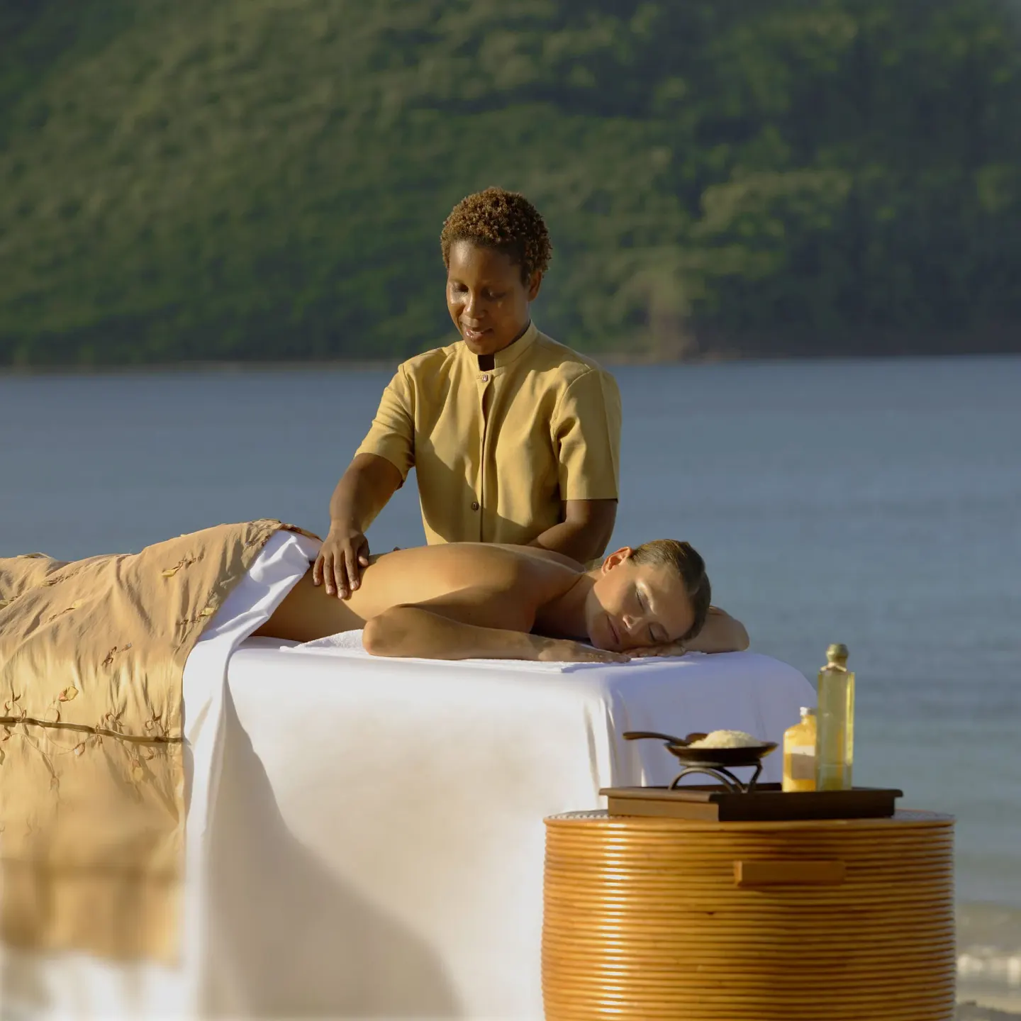 Beachfront massage table beside calm water at The Landings Resort & Spa.