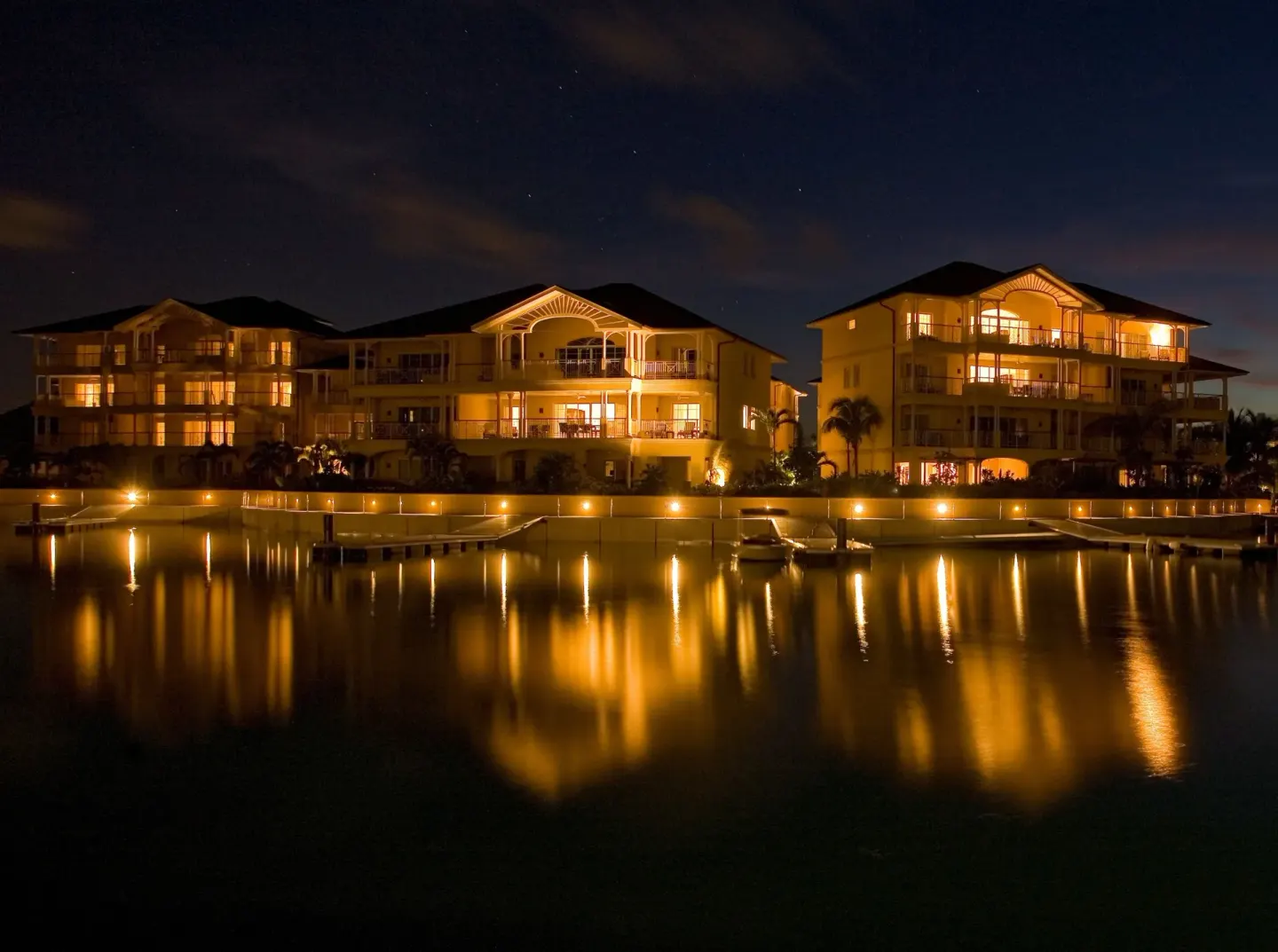 Nighttime marina buildings glow beside the water at The Landings Resort & Spa.