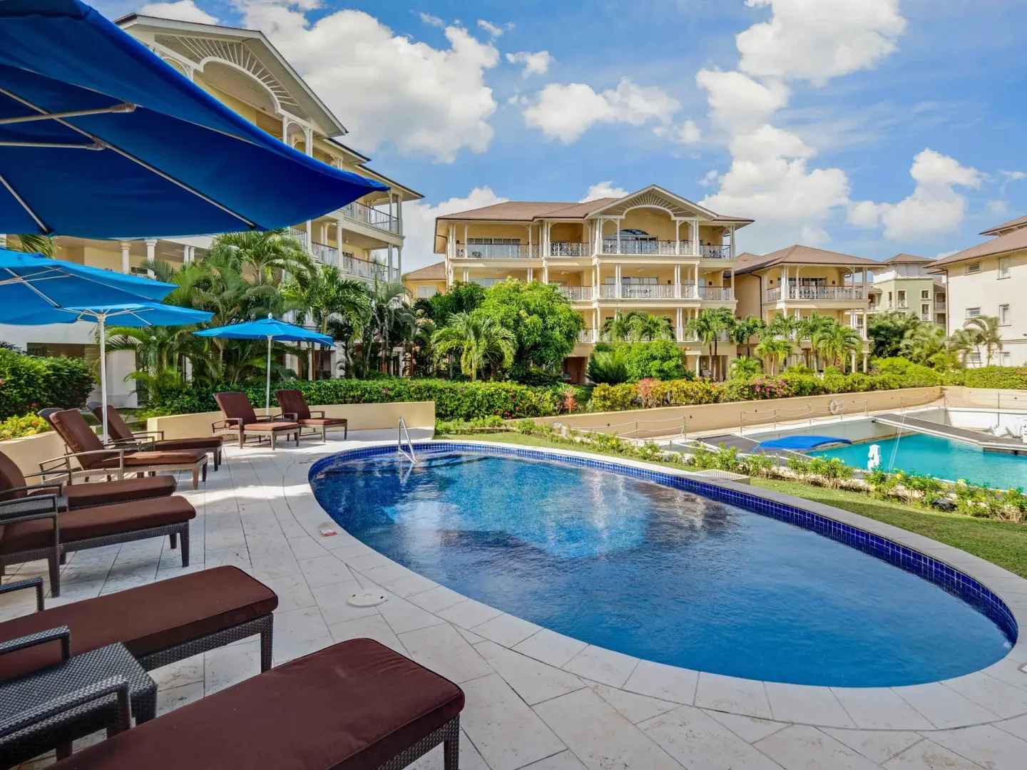 Oval pool with loungers, blue umbrellas and balconies at The Landings Resort & Spa.