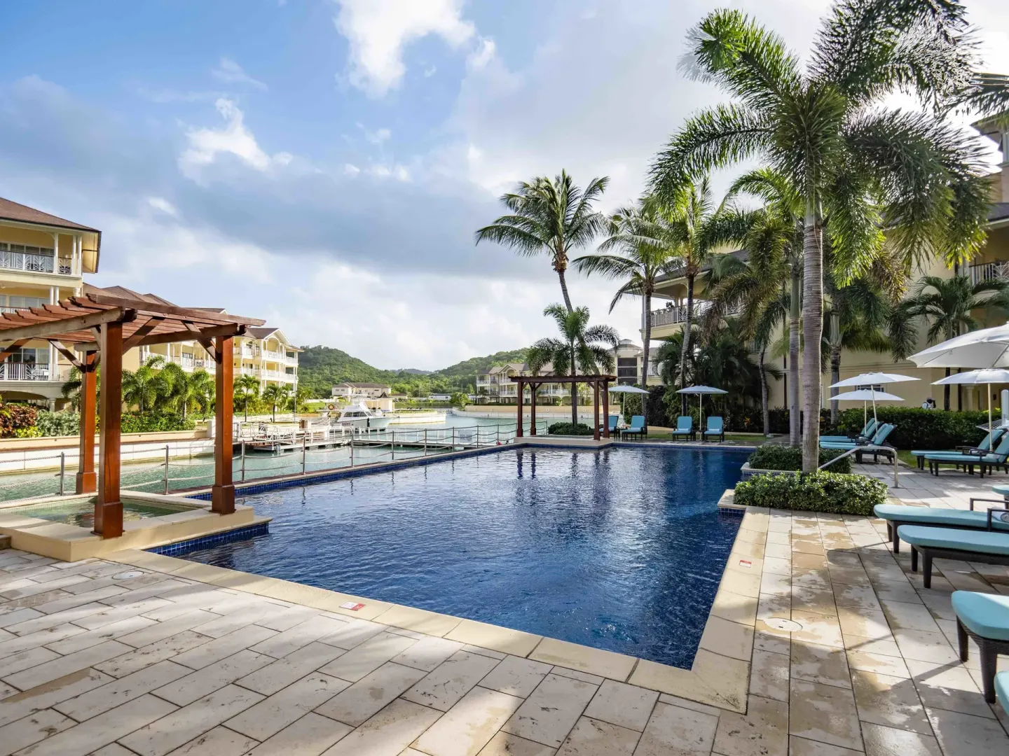 Pool deck with loungers, palms and marina beyond at The Landings Resort & Spa.