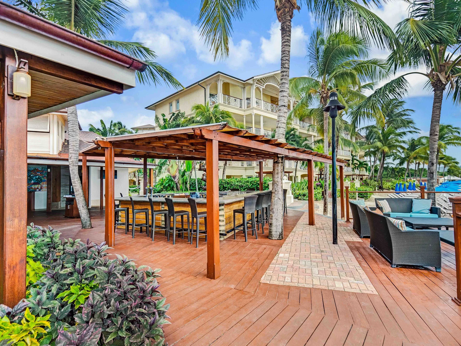 Beachside wooden bar and lounge seating among palms at The Landings Resort & Spa.
