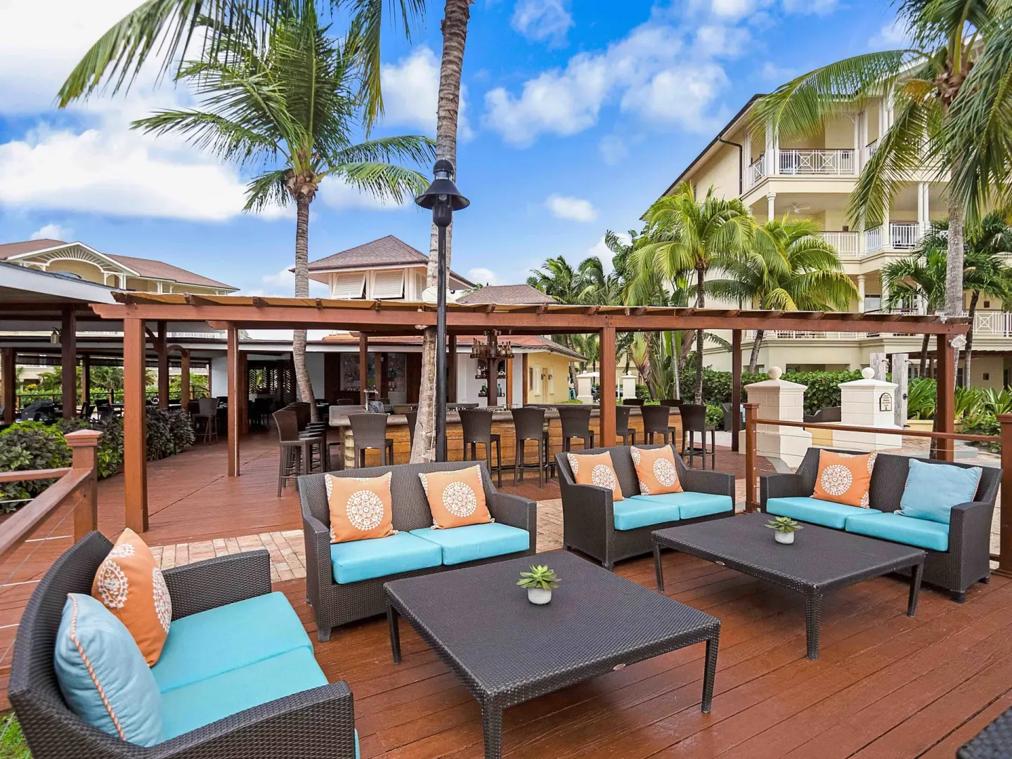 Outdoor lounge sofas and bar seating on a palm-lined deck at The Landings Resort & Spa.