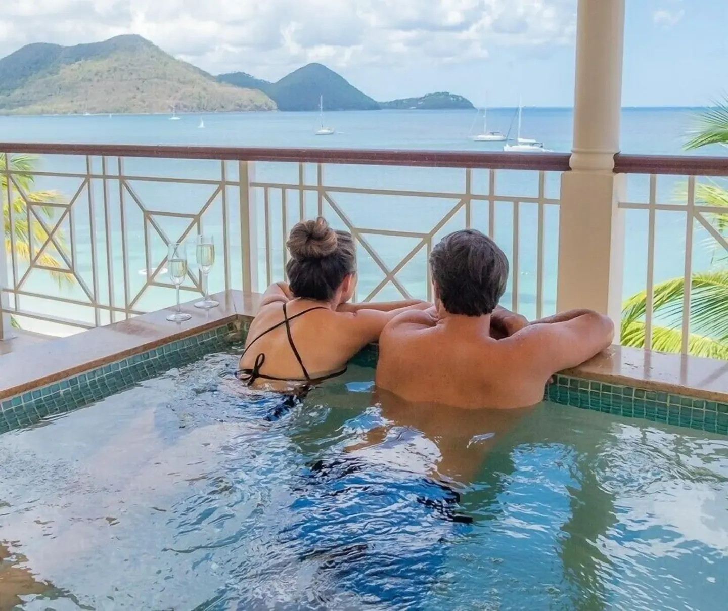 Guests in a balcony plunge pool at The Landings Resort & Spa overlooking the sea and sailboats.