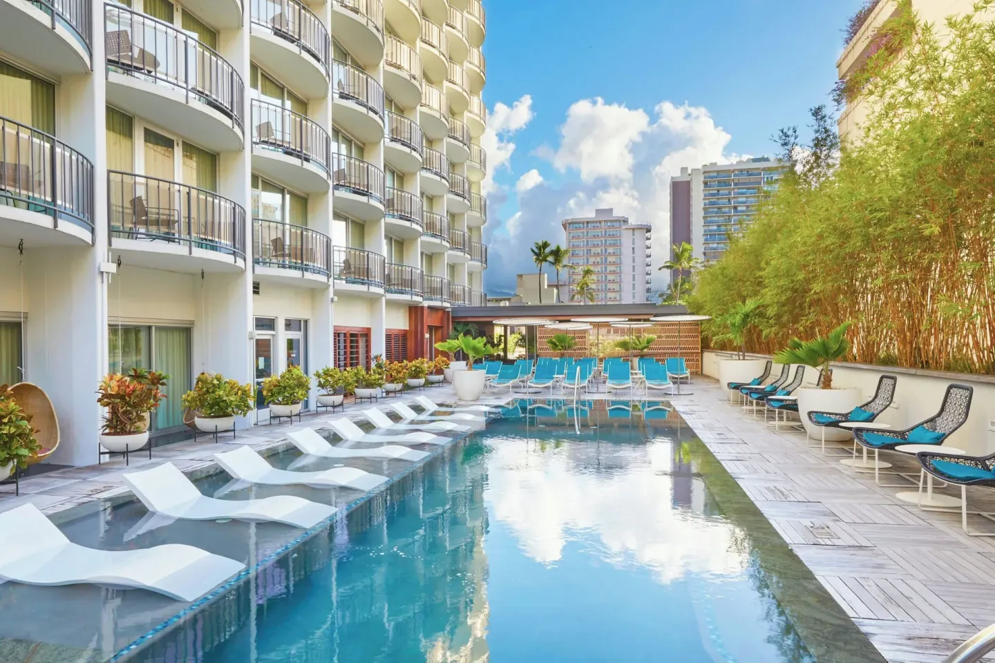 Pool deck with loungers and balconies at The Laylow Waikiki, Autograph Collection.