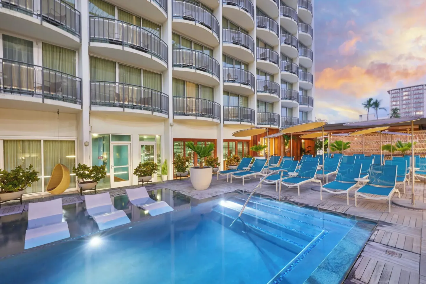 Pool deck with lounge chairs and balconies at The Laylow Waikiki, Autograph Collection.