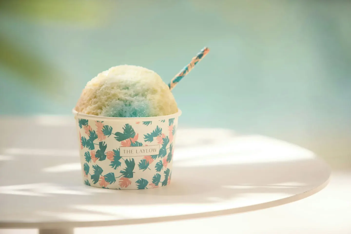 Shave ice in a patterned cup sits poolside at The Laylow Waikiki, Autograph Collection.