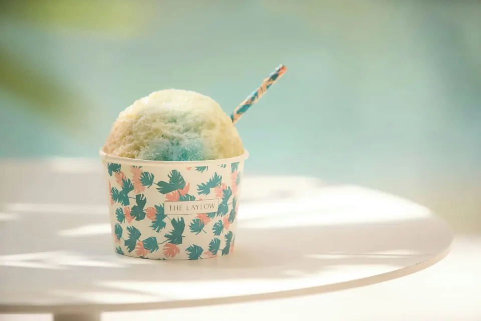 Shave ice in a patterned cup sits poolside at The Laylow Waikiki, Autograph Collection.