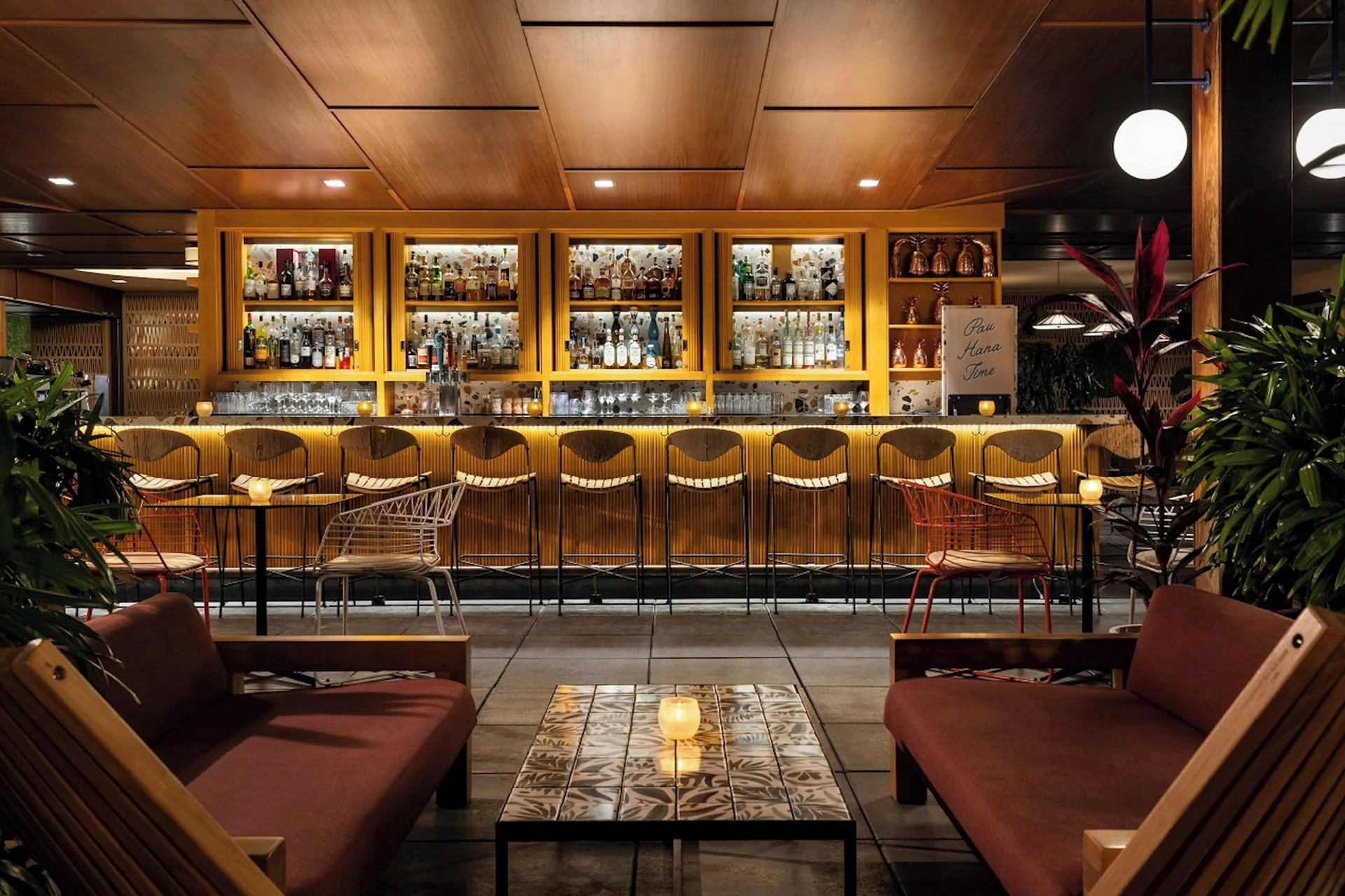 Indoor-outdoor bar seating and lounge chairs at The Laylow Waikiki, Autograph Collection.