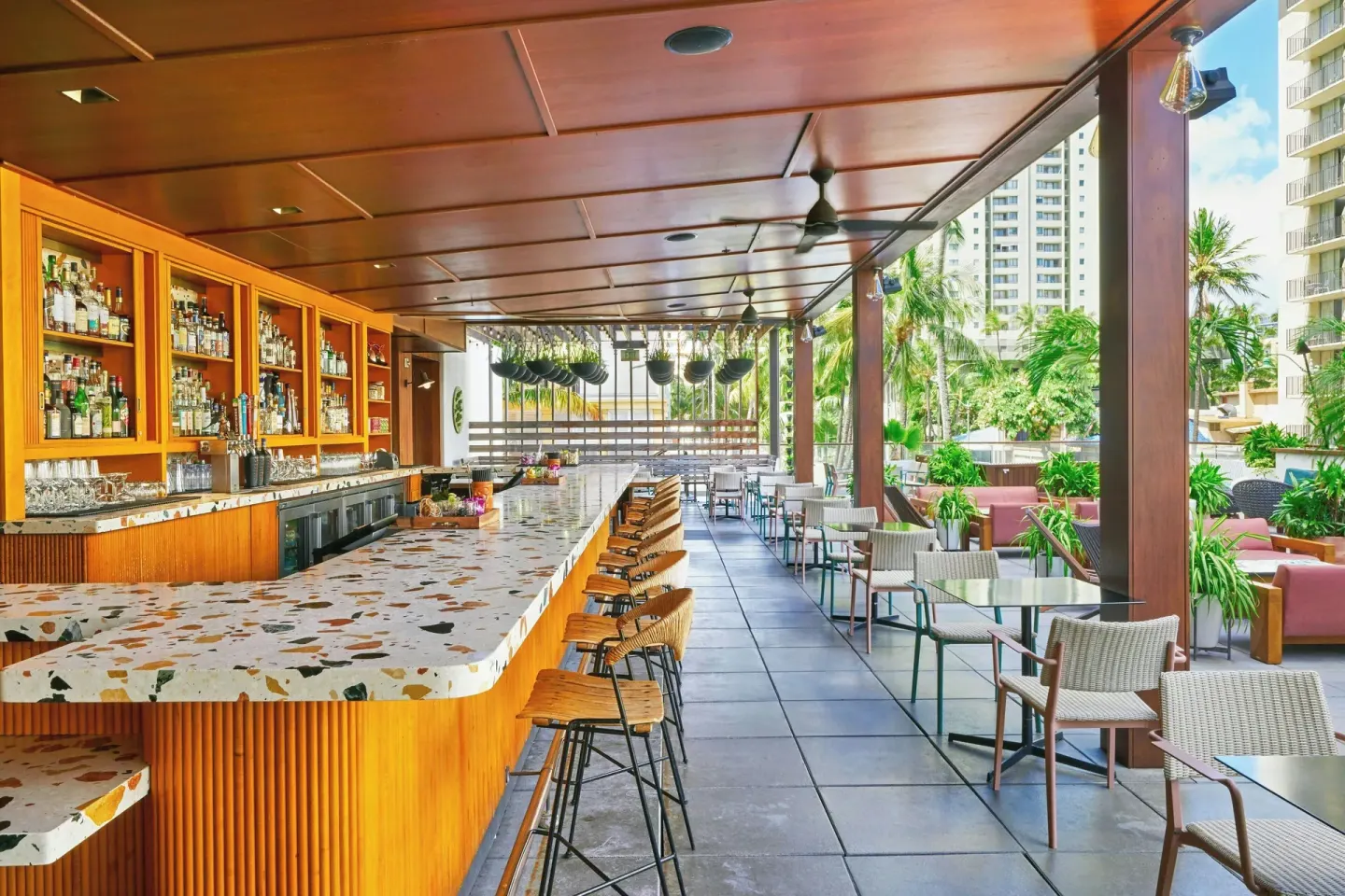 Long open-air bar with counter seating at The Laylow Waikiki, Autograph Collection.