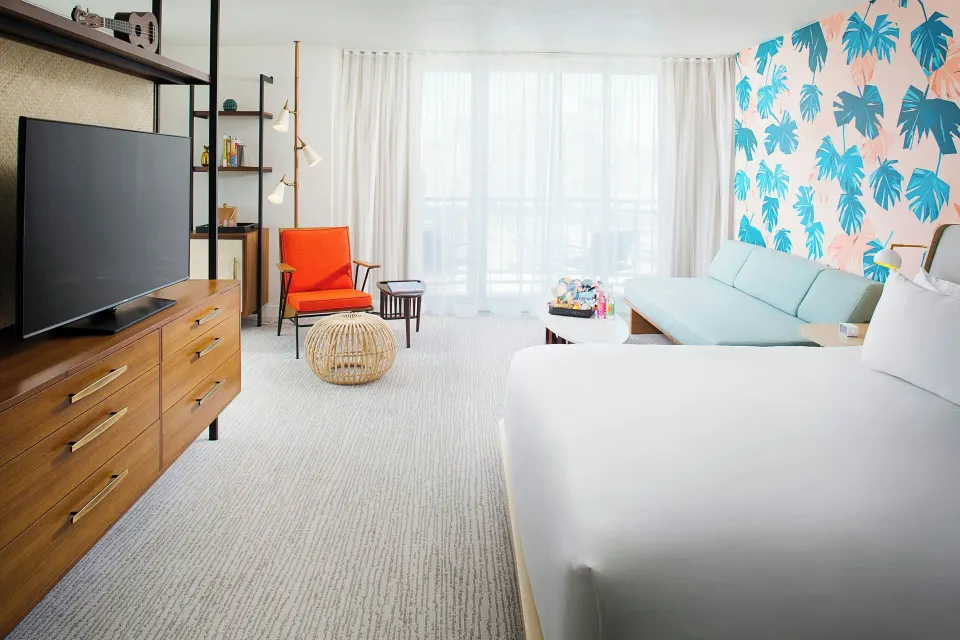 Corner Suite with king bed, daybed, TV, and balcony curtains at The Laylow Waikiki, Autograph Collection.
