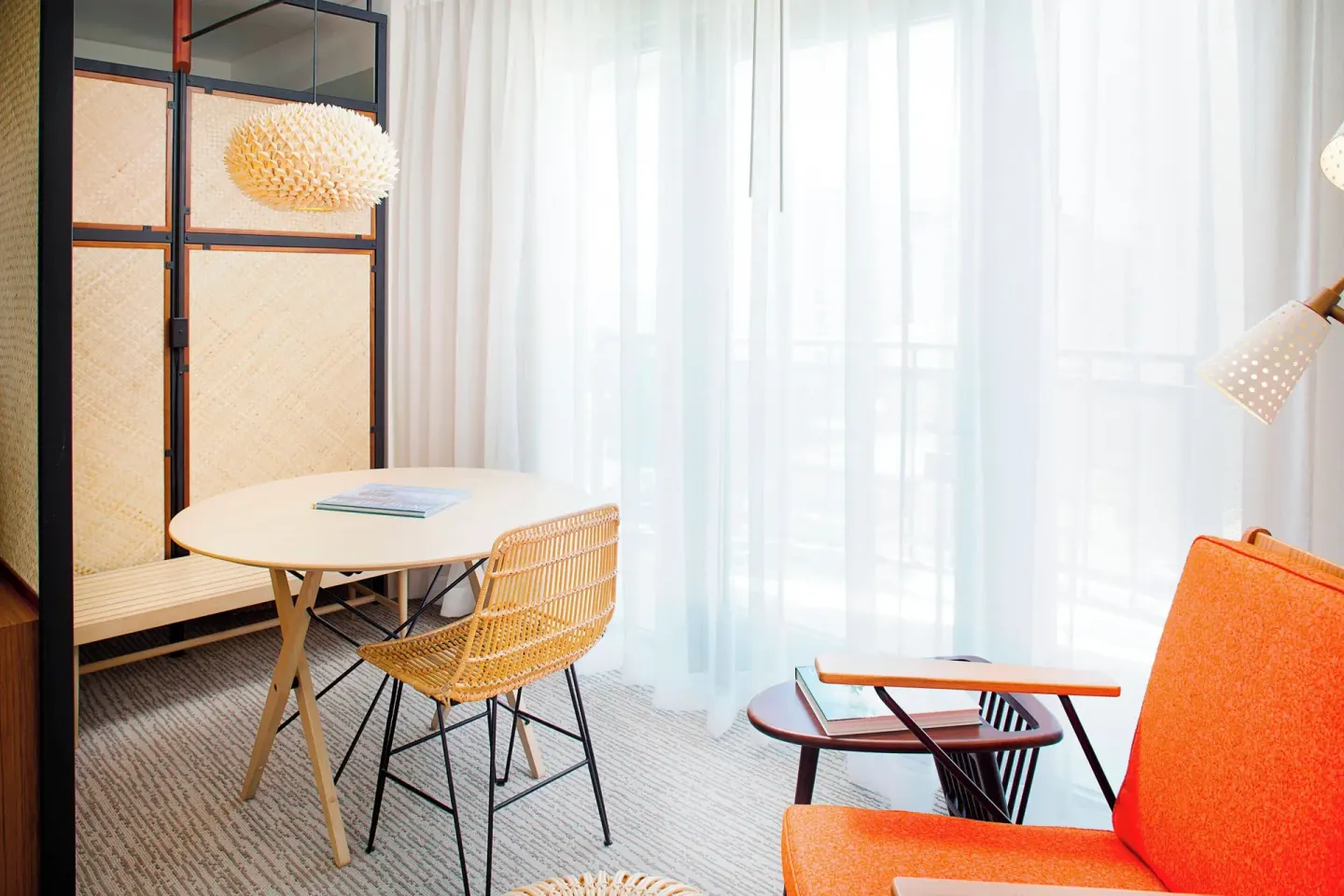 Corner Suite seating area with round table and orange chair at The Laylow Waikiki, Autograph Collection.