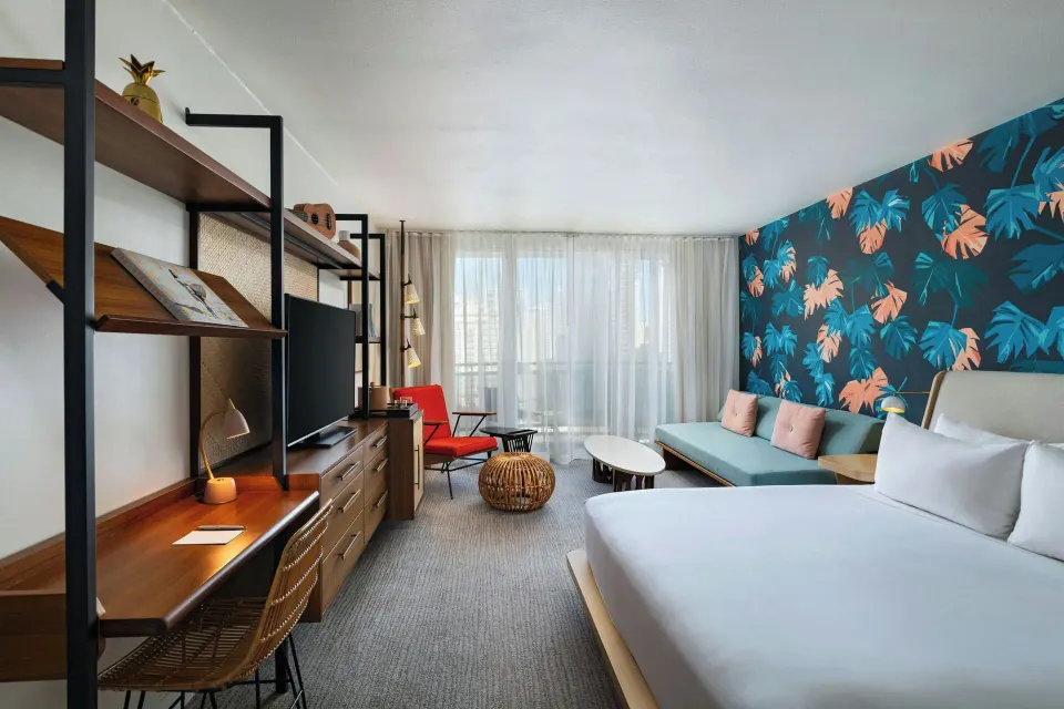 King bed and daybed guestroom with balcony doors at The Laylow Waikiki, Autograph Collection.