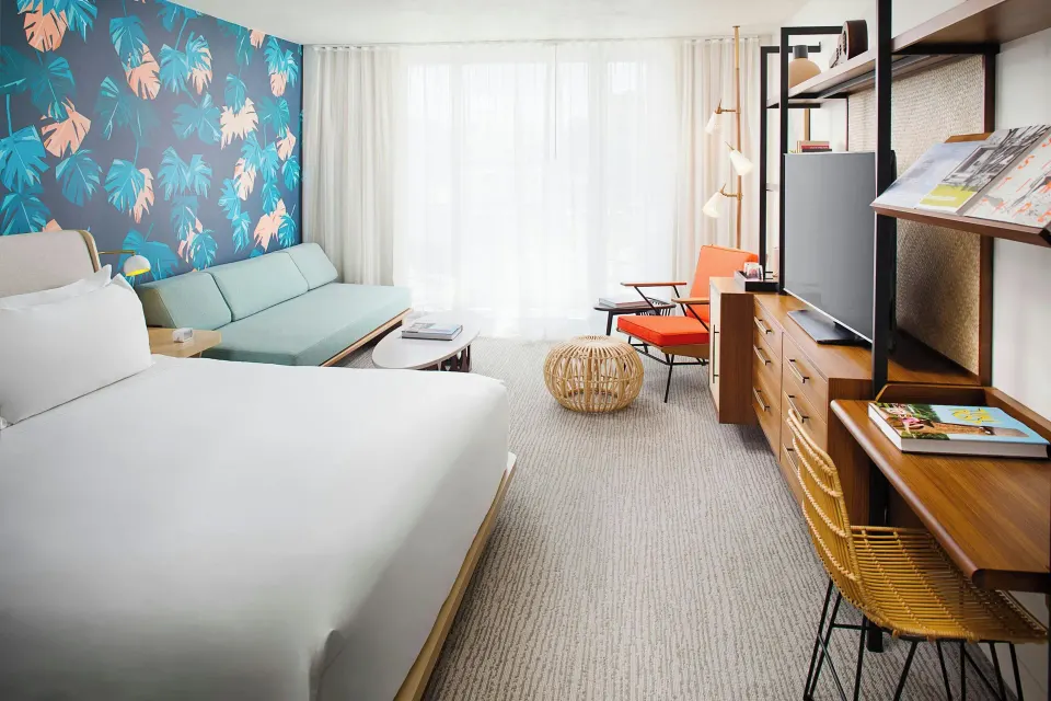Guestroom with bed, daybed, desk, and balcony curtains at The Laylow Waikiki, Autograph Collection.