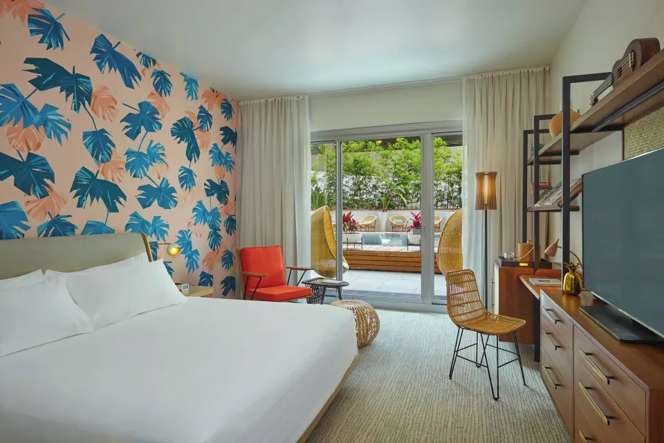 King guest room with tropical wall and patio doors at The Laylow Waikiki, Autograph Collection.
