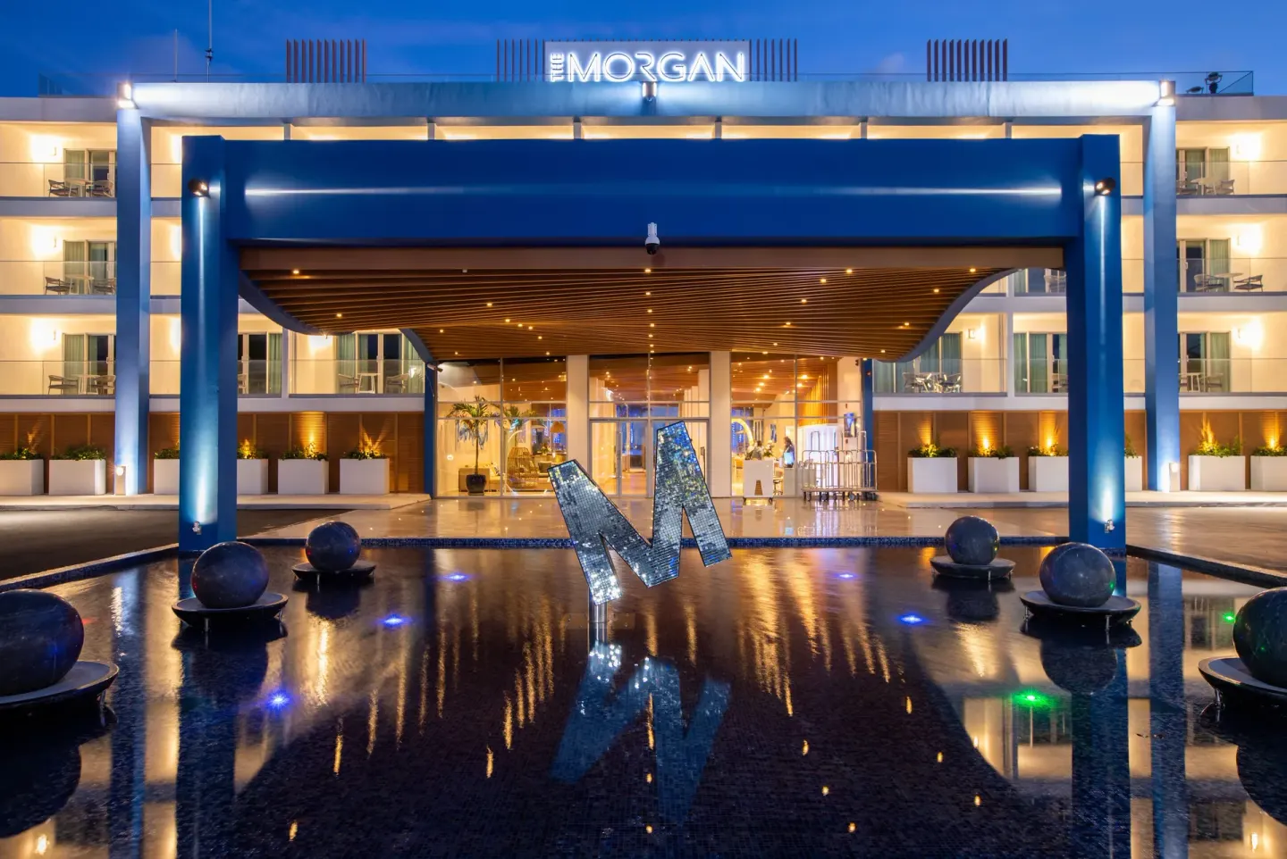 Illuminated entrance and reflecting pool at The Morgan Resort Spa Village.