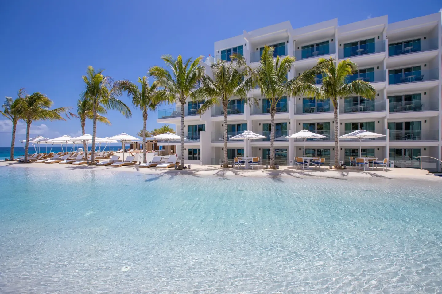 Resort pool, palm trees, umbrellas, and guest balconies at The Morgan Resort Spa Village.