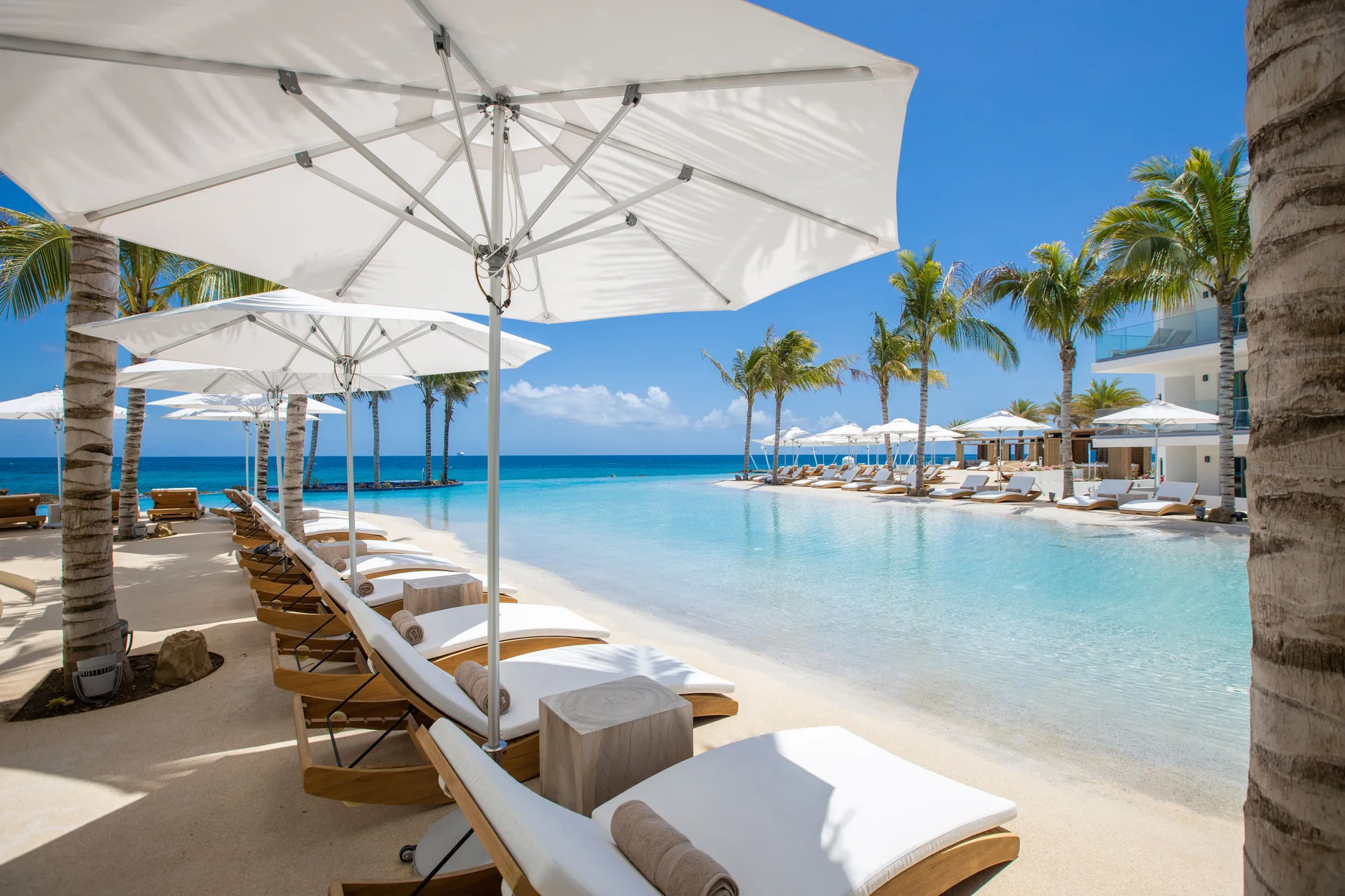 White loungers and umbrellas line the pool overlooking the sea at The Morgan Resort Spa Village.