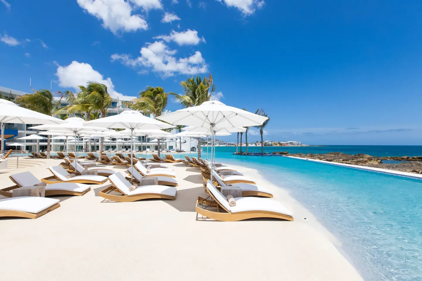 Oceanfront loungers and umbrellas beside the pool at The Morgan Resort Spa Village.