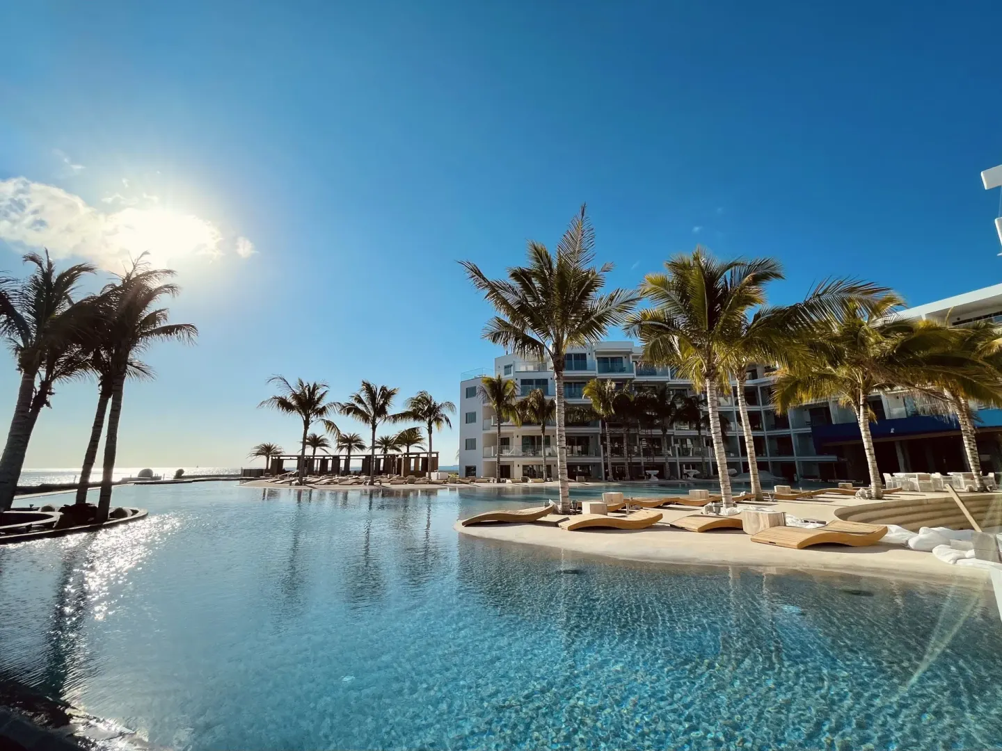 Pool deck at The Morgan Resort Spa Village with palms, loungers, and resort buildings.