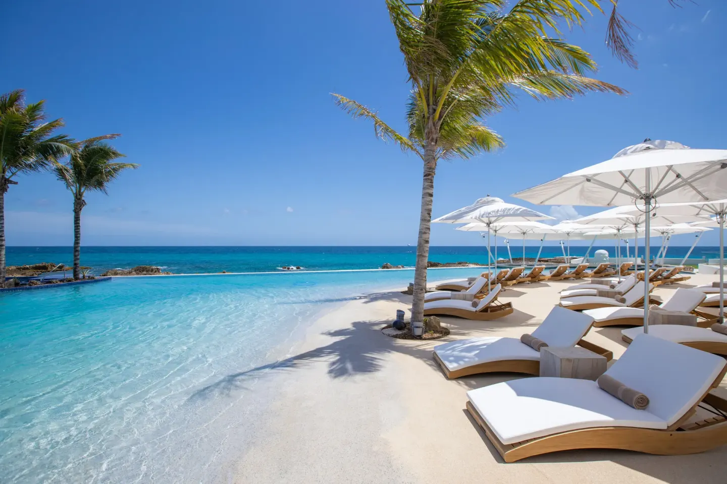 Sun loungers and white umbrellas along the pool edge at The Morgan Resort Spa Village.