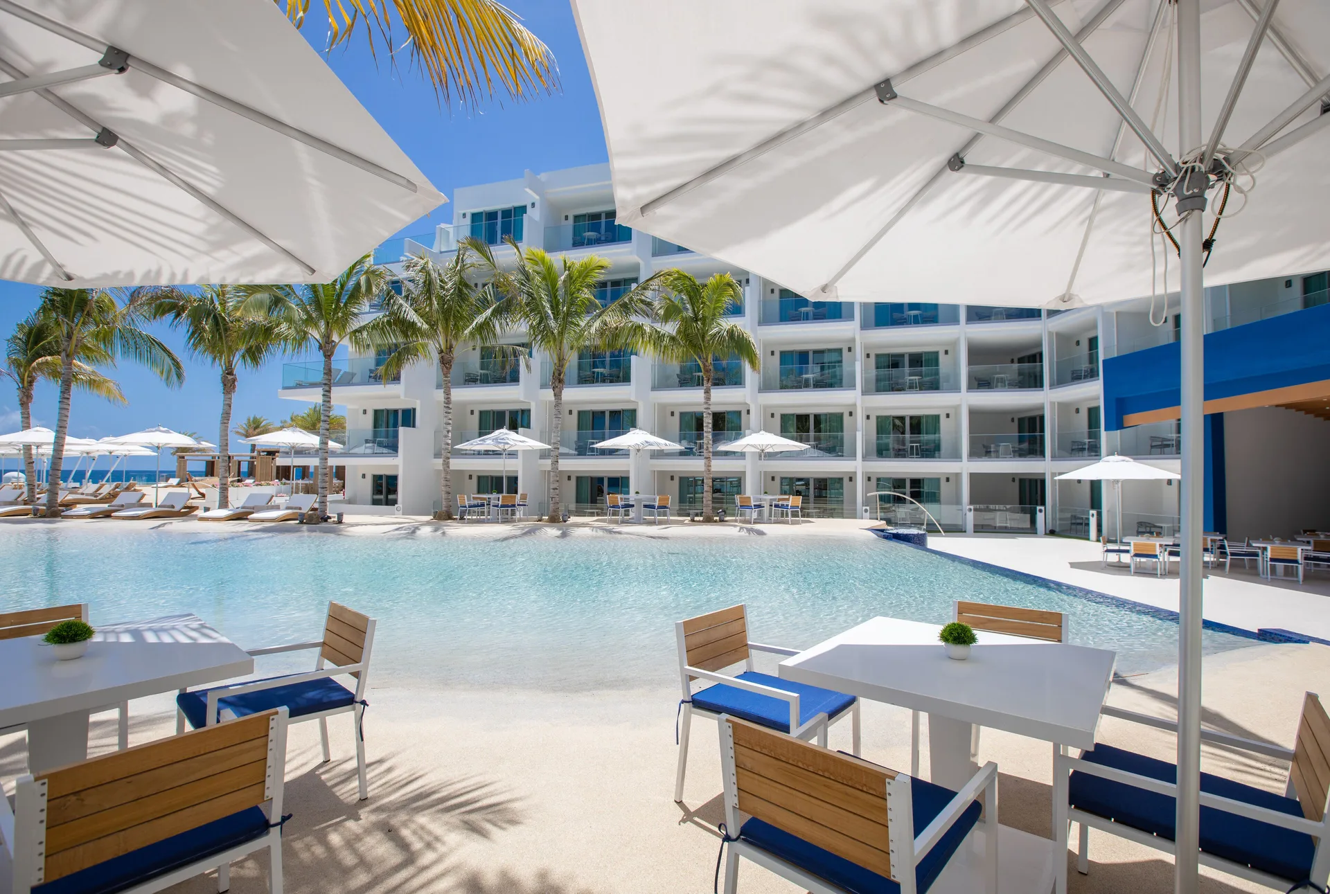 Outdoor tables under umbrellas overlook the pool at The Morgan Resort Spa Village.