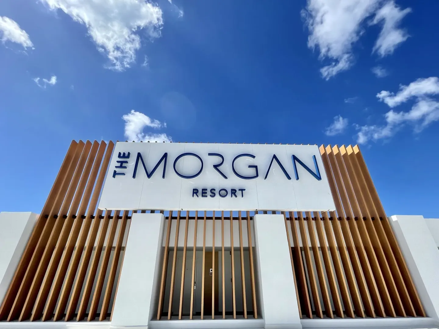 Entrance sign for The Morgan Resort Spa Village set against a bright blue sky.