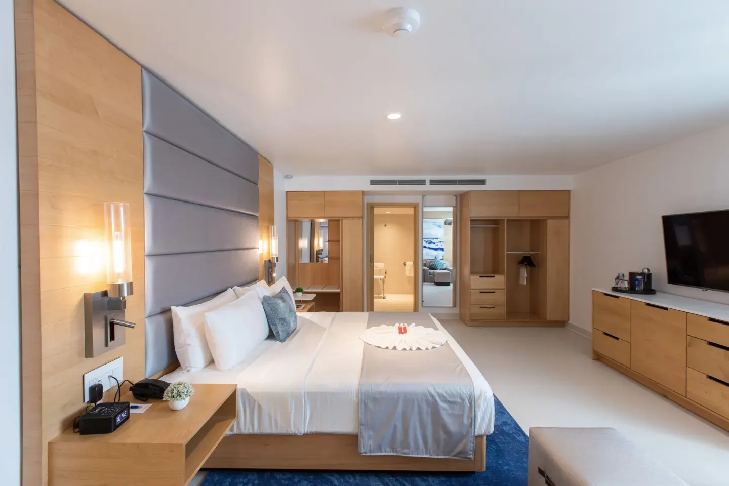 Accessible guestroom king bed with open wardrobe and dresser at The Morgan Resort Spa Village.