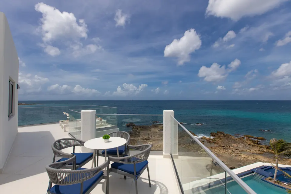 Deluxe Oceanfront Suite balcony with table, chairs and sea view at The Morgan Resort Spa Village.