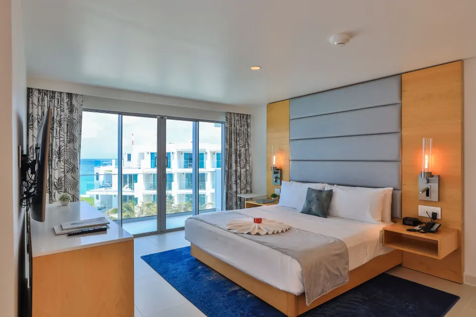 Deluxe Oceanfront Suite king bed facing balcony doors at The Morgan Resort Spa Village.