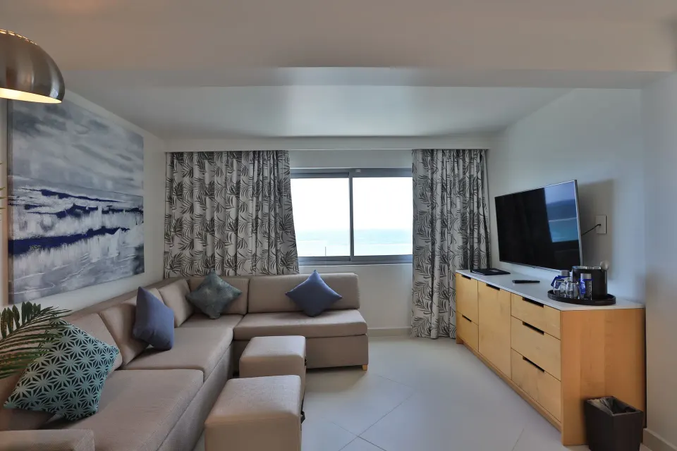 Deluxe Oceanfront Suite sitting room with TV and sea view at The Morgan Resort Spa Village.