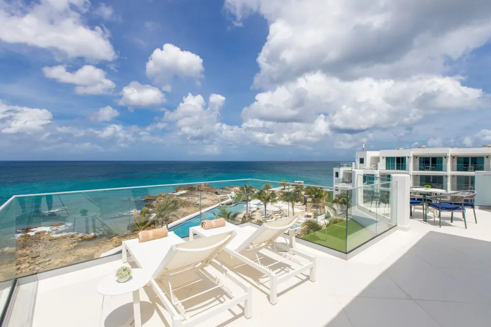 Deluxe Oceanfront Suite terrace with loungers and ocean view at The Morgan Resort Spa Village.