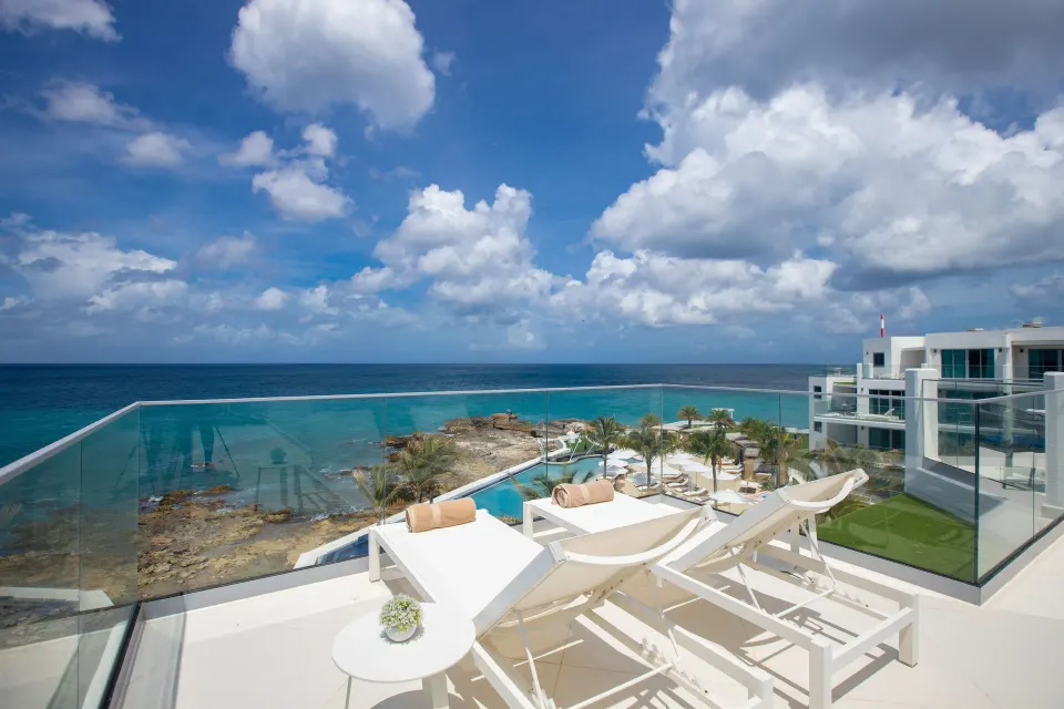 Deluxe Oceanfront Suite terrace with loungers and resort views at The Morgan Resort Spa Village.