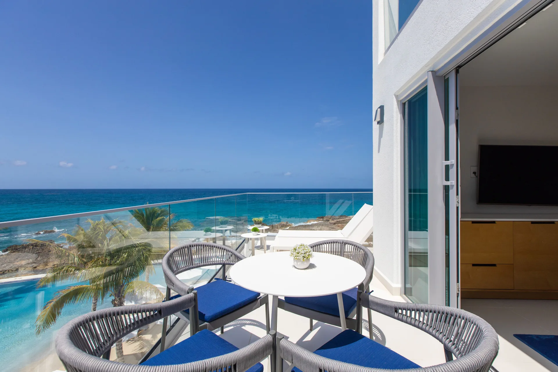 Junior Oceanfront Suite balcony seating by sliding doors at The Morgan Resort Spa Village.
