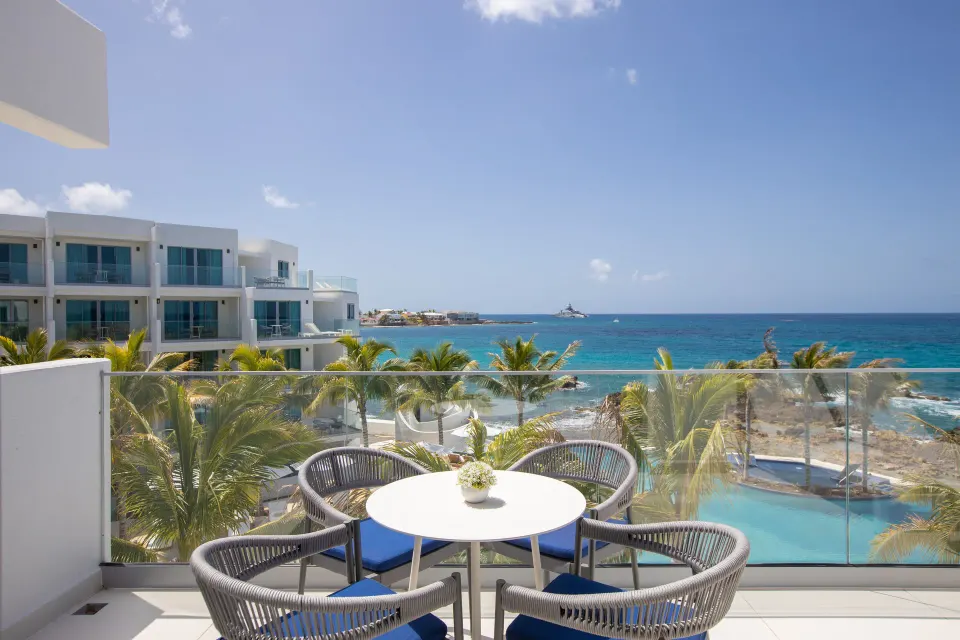 Junior Oceanfront Suite balcony with table, chairs, and sea view at The Morgan Resort Spa Village.