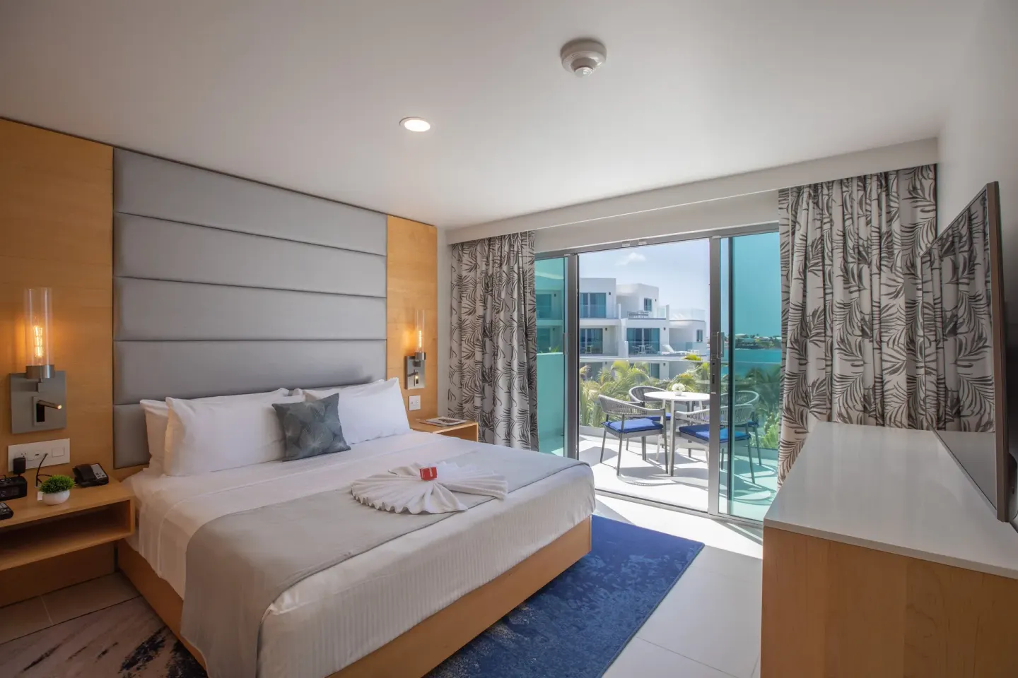 Junior Oceanfront Suite bedroom with king bed and balcony at The Morgan Resort Spa Village.