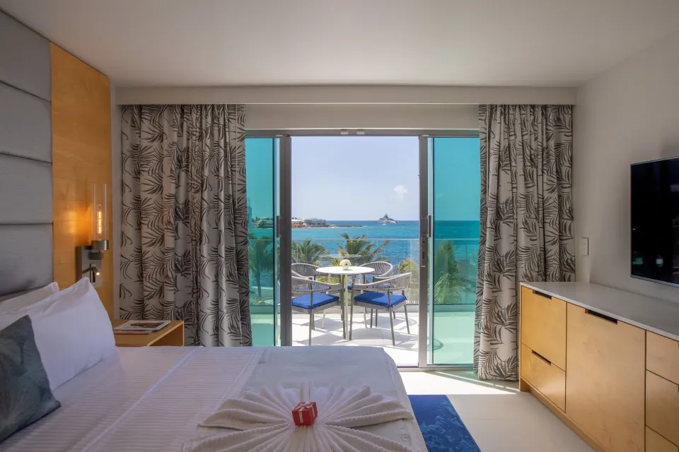 Junior Oceanfront Suite king bed facing a balcony and ocean view at The Morgan Resort Spa Village.