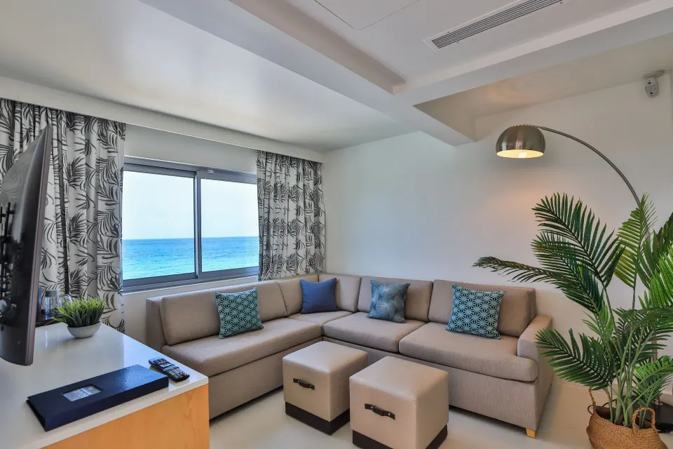 Junior Oceanfront Suite sitting area with sectional sofa and sea view at The Morgan Resort Spa Village.