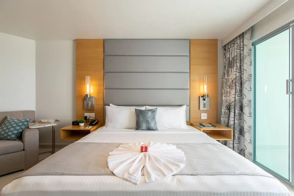 Oceanview guestroom king bed with balcony doors at The Morgan Resort Spa Village.