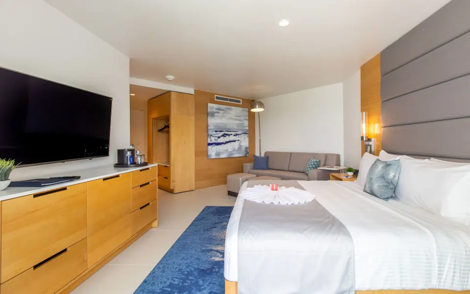 Pool View Guestroom with king bed, sofa, TV, and wood cabinetry at The Morgan Resort Spa Village.